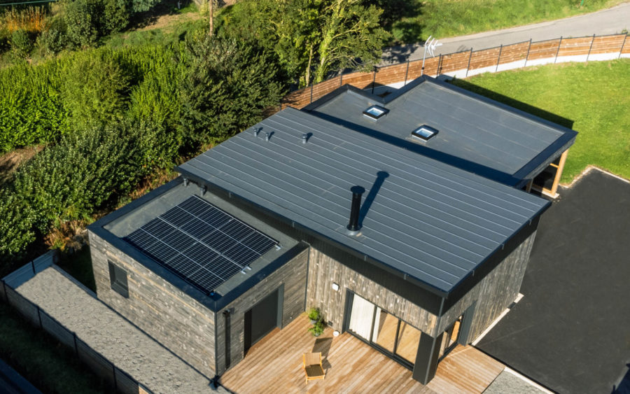 panneaux solaires posés sur le toit plat d'une extension de maison en bois.
